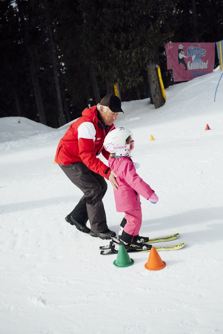 Skischulleiter Told hilft einer kleinen Schülerin. Sie soll auf Skiern durch einen Parcours aus Hütchen manövrieren. „Ein bisschen Rumrutschen, ein Gefühl für die Skier bekommen – mehr braucht es am Anfang nicht“, sagt Told.