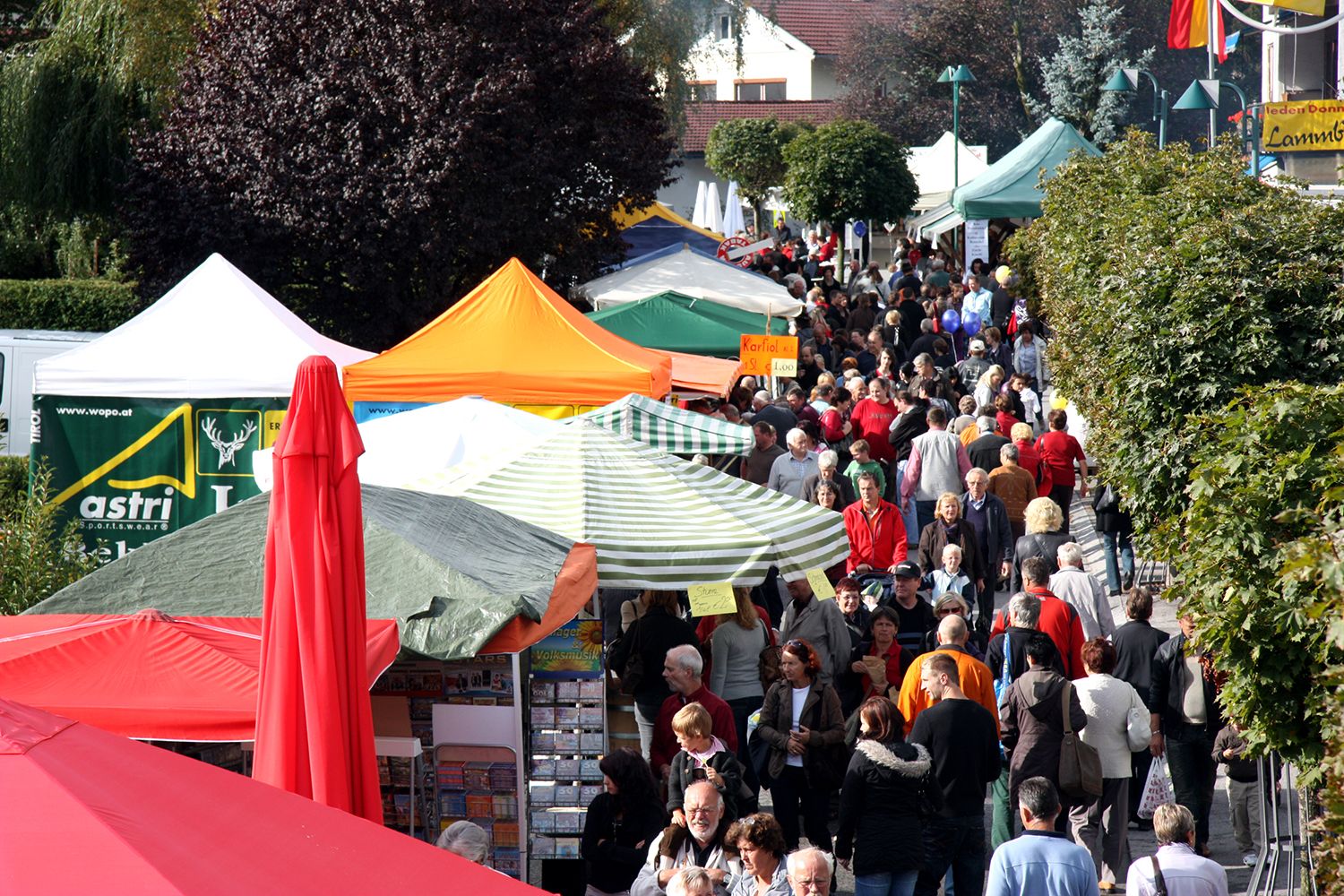 Bunte Marktstände, Besucher schlendern an den Ständen entlang