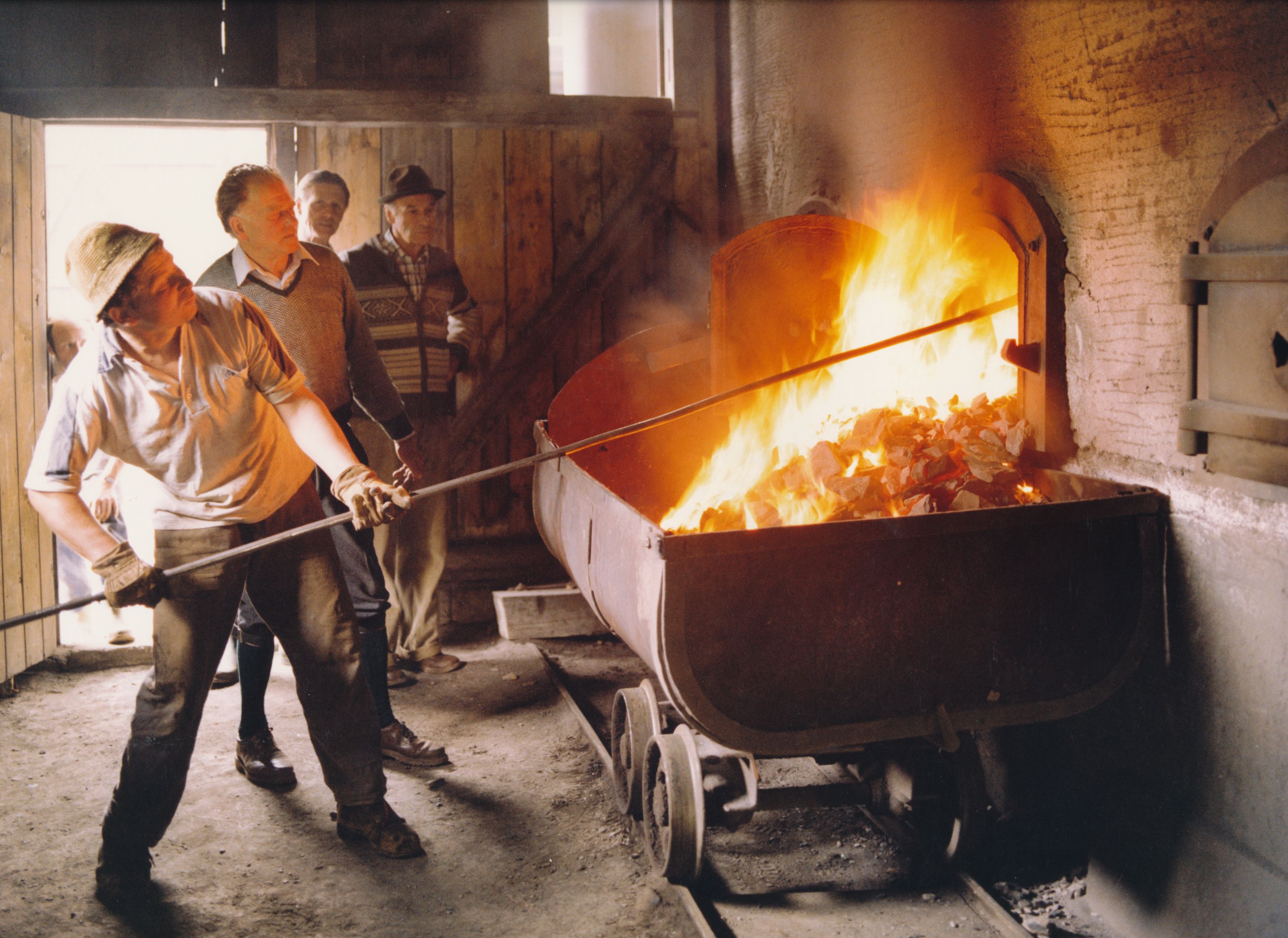 Zwei Männer bei der Herstellung von Steinöl vor dem offenen Feuer