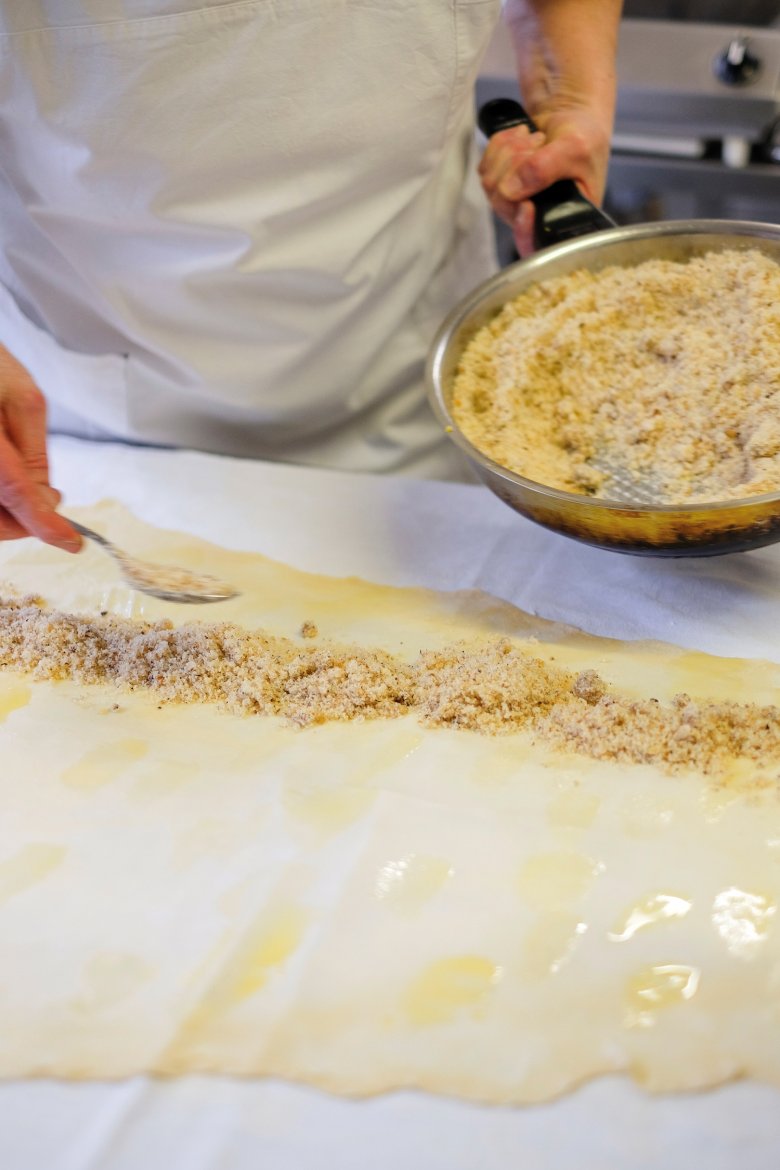 Der hauchd&uuml;nn ausgezogene Teig wird mit zerlassener Butter bestrichen und mit F&uuml;llung belegt.

