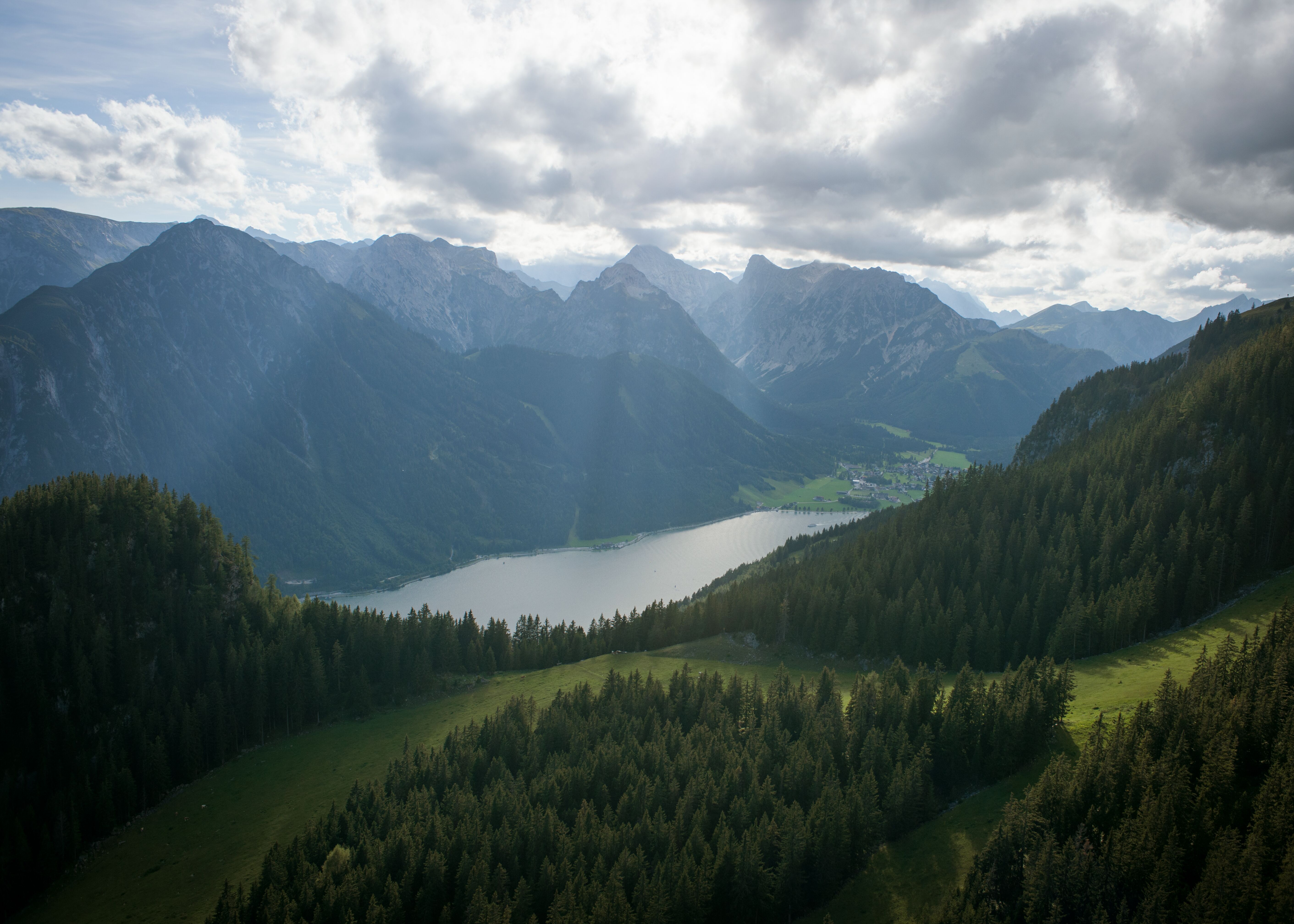 Der Achensee aus der Vogelperspektive. Durch die Wolkendecke brechen Sonnenstrahlen.